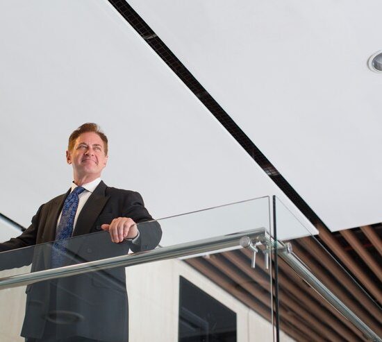 smiling-mature-businessman-standing-office-hall_1262-3105